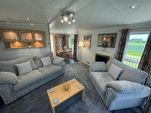 a living room with two couches and a table at Millfields Holiday Park - Knightsbridge Deluxe - Coastal Caravan Breaks in Ingoldmells