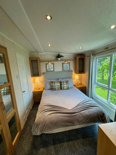a bedroom with a large bed with two lights on at Millfields Holiday Park - Knightsbridge Deluxe - Coastal Caravan Breaks in Ingoldmells