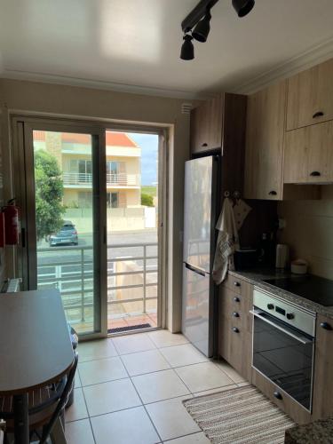 una cucina con frigorifero e una porta che conduce a un balcone. di Maura's Holiday House a Silveira