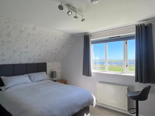 ein Schlafzimmer mit einem Bett und einem großen Fenster in der Unterkunft Aultnagar Accommodation in Orkney