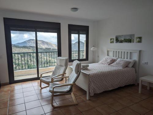 a bedroom with a bed and two chairs and windows at Alojamientos Turisticos Isa i Toni in Sella