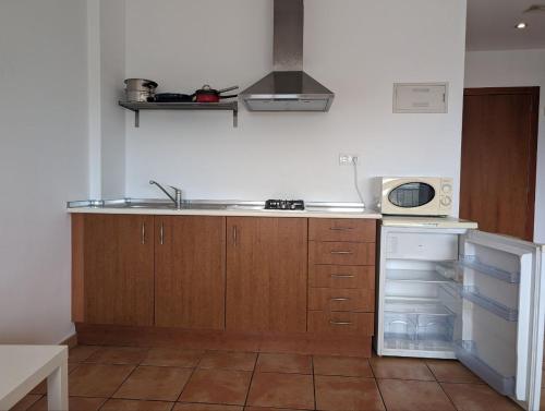 a kitchen with a sink and a stove and a microwave at Alojamientos Turisticos Isa i Toni in Sella