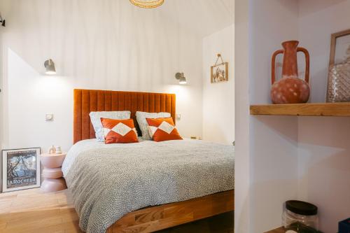 a bedroom with a bed with orange and gray pillows at Élégance Rochelaise avec Terrasse in La Rochelle