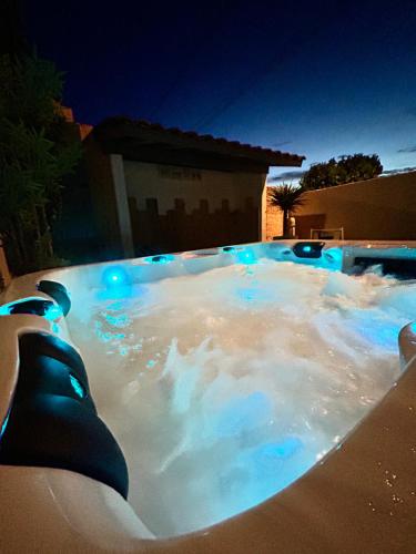 un bain à remous avec des lumières bleues dans une arrière-cour dans l'établissement L Oustalet Maison avec Spa proche Mer, à Sérignan