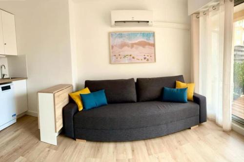 un salon avec un canapé noir dans une cuisine dans l'établissement Grande terrasse Cœur Port Fréjus 5 pers, à Fréjus