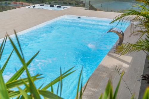 a large blue swimming pool with a wooden deck at Finca Encanto in Calimita