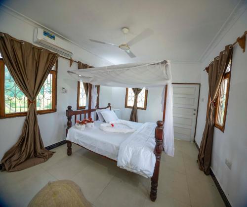 - une chambre avec un lit à baldaquin dans l'établissement Mangapwani Beach villa, à Fujoni