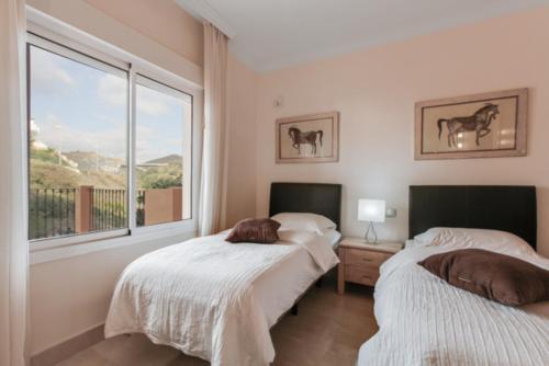 two beds in a room with a window at Aloha Hill Club LLuxury 5 Star Golf Resort Near Puerto Banus and Marbella in Marbella