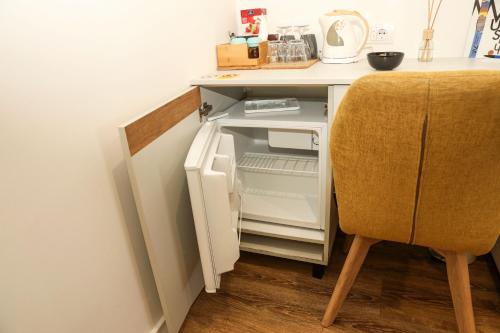 a white refrigerator with its door open next to a chair at Business Suite Novi Sad Center in Novi Sad