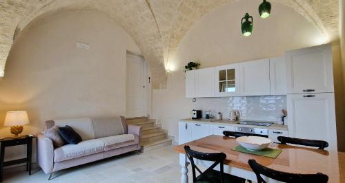 a kitchen and living room with a table and a couch at Corte Dioniso Eco Apartments & Suites in Crispiano
