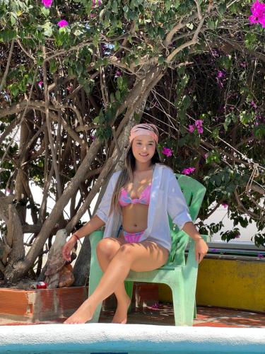 a woman sitting in a chair next to a pool at Hotel Casa Grande Riohacha Inn in Ríohacha