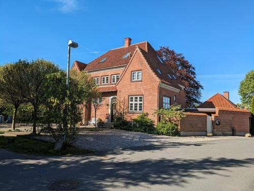 Gæstehus Sorø Sø في سورو: منزل من الطوب كبير أمامه شجرة