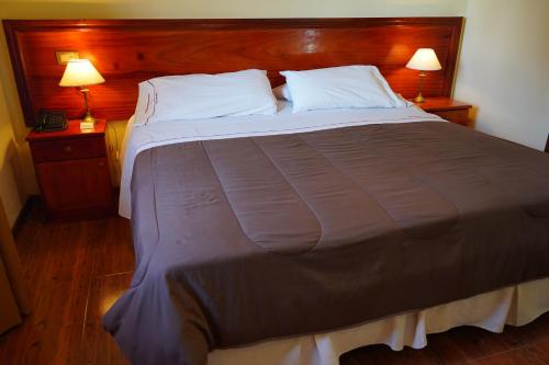 a large bed in a bedroom with two lamps on tables at Hosteria Sirenuse in Mar del Plata