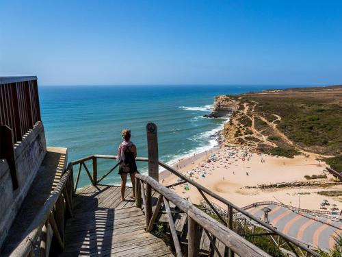 a woman standing on a staircase looking at the beach at T1 Casa da Quinta in Mafra