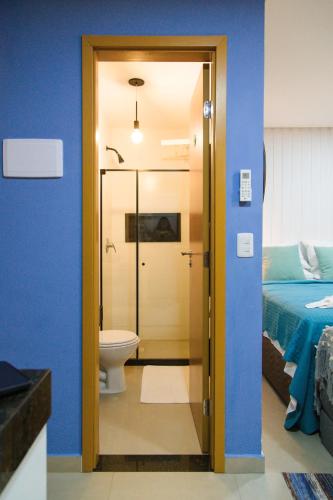 a bathroom with a shower and a toilet and a bed at Maracaipe Estrela Flat110 in Porto De Galinhas