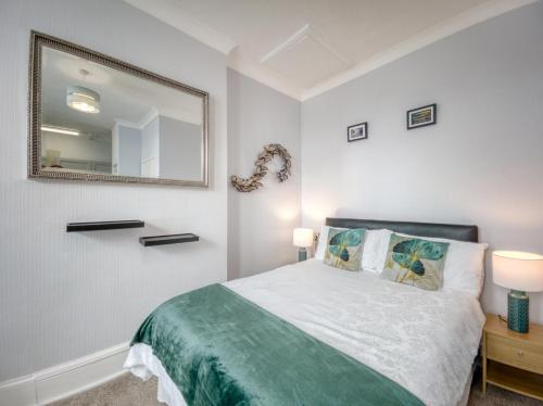 1 dormitorio con cama y espejo en la pared en Apartment 4 - Large studio - Sea Front location - Rear views-Free Parking, en Paignton