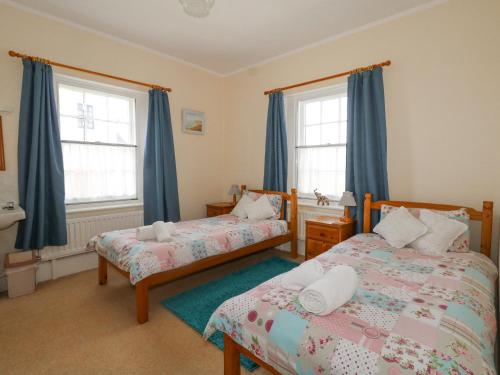a bedroom with two beds and blue curtains at Old Higher Lighthouse Stopes Cottage in Southwell