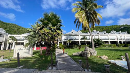 a large white building with palm trees in front of it at Island Escape, Marina Paradise & Beach Adventures in Saint Martin