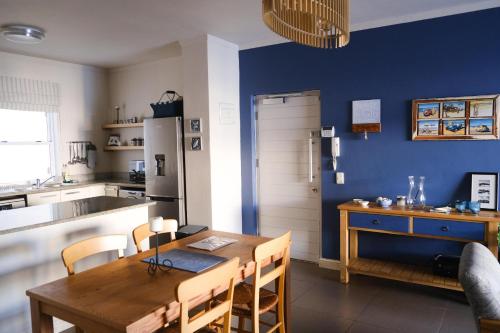 cocina con mesa de madera y pared azul en Penguin Paradise Apartment Simons Town en Simonʼs Town