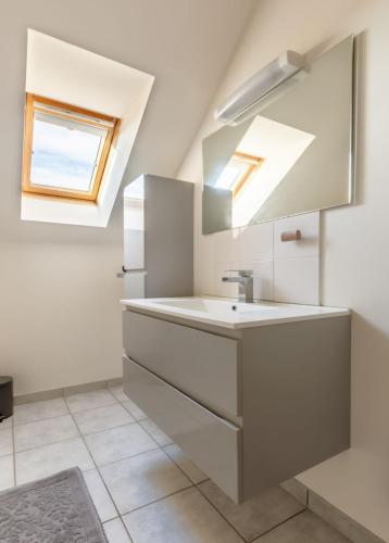 une salle de bain avec un lavabo et un miroir dans l'établissement Maison au calme, à Bayeux