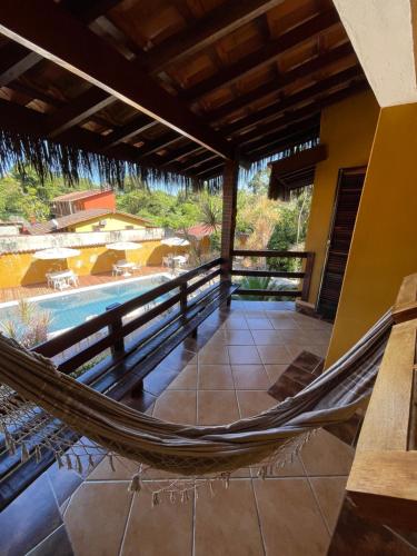 a hammock on the porch of a house with a pool at Pousada In Bali - Maresias in Maresias