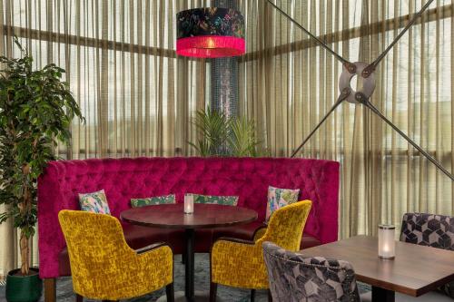 a dining room with a red couch and tables and chairs at Crowne Plaza Dublin Blanchardstown by IHG in Blanchardstown