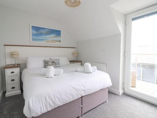 a bedroom with a white bed with two stuffed animals on it at Flip Flops in Reighton