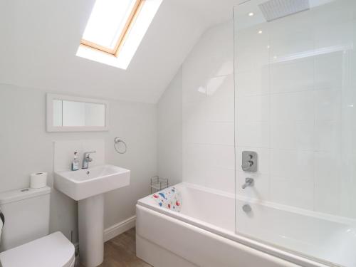 a white bathroom with a sink and a bath tub at Flip Flops in Reighton