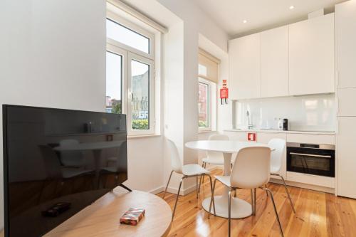 a kitchen with white cabinets and a table and chairs at Arroios Concept Apartments by Homing in Lisbon