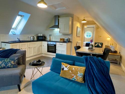 a living room with a blue couch and a kitchen at Cheshire Retreat in Middlewich