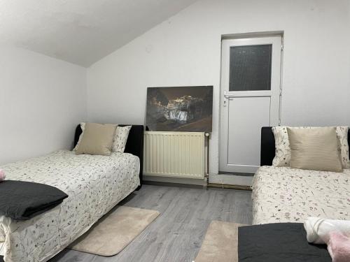 a bedroom with two beds and a window and a door at Pougarka Apartments in Jajce
