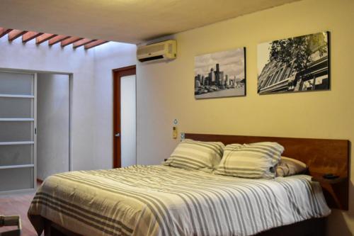- une chambre avec un lit et deux photos sur le mur dans l'établissement Valentin House, very spacious and cozy., à San Luis Potosí