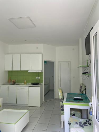 Una cocina con gabinetes blancos y una mesa. en Apartmani Jovana, en Soko Banja