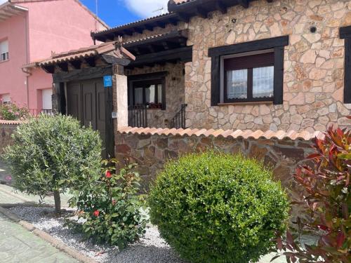 Una casa de piedra con una puerta negra y algunos arbustos. en Casa La Divisa, en Boceguillas