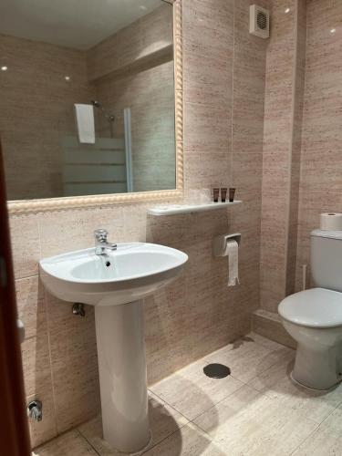 a bathroom with a sink and a toilet and a mirror at Fleming Center by Punta 25 Hotels Group in Benidorm