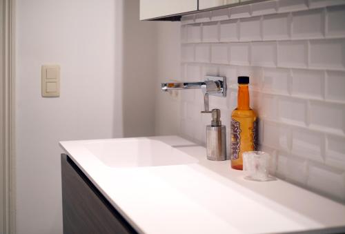 a kitchen counter with a sink and a bottle of alcohol at Your homestay in a bibliophile mansion in Antwerp