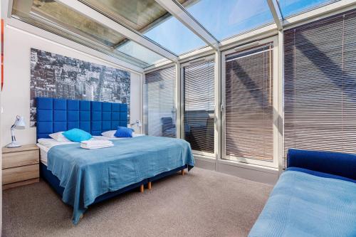 - une chambre avec un lit bleu et de grandes fenêtres dans l'établissement MS Apart Władysławowo, à Władysławowo