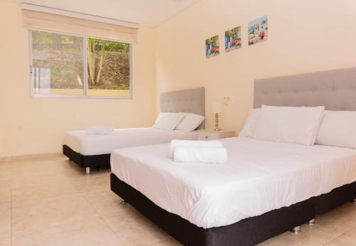 1 dormitorio con 2 camas y ventana en Casa Campestre - Pet Friendly - Green Energy, en Anapoima