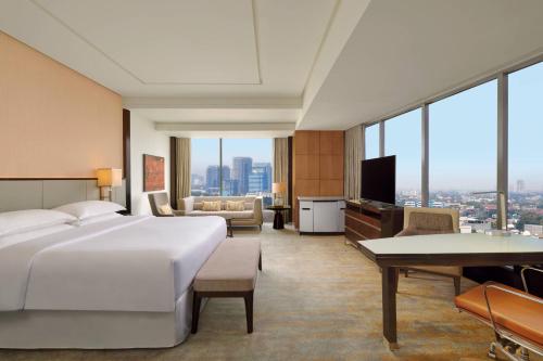 a hotel room with a large bed and a living room at Sheraton Grand Jakarta Gandaria City Hotel in Jakarta