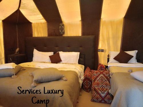 a bedroom with two beds with stuffed animals on them at Services Luxury Camp in Merzouga