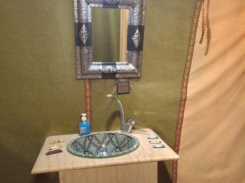 a bathroom with a sink and a mirror at Services Luxury Camp in Merzouga