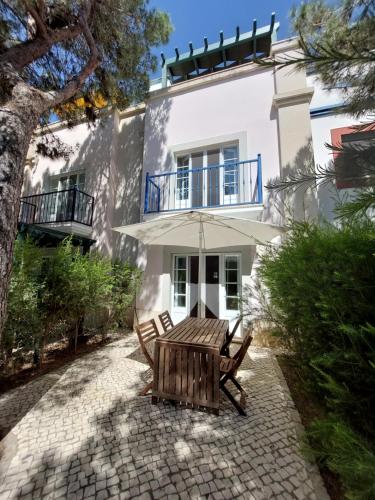 a white house with two chairs and an umbrella at Casa Água & Sal in Praia Verde