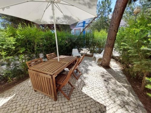 a wooden table and chairs with an umbrella at Casa Água & Sal in Praia Verde