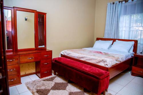 a bedroom with a bed and a dresser and a red stool at Faba court in Kampala