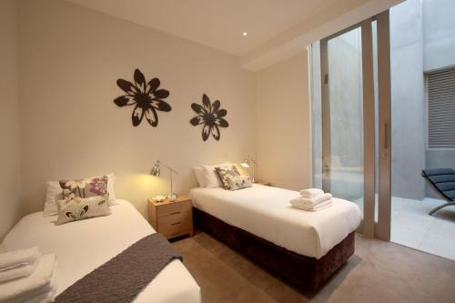 1 dormitorio con 2 camas y baño con ventana en Boutique Stays - The Residence, en Melbourne