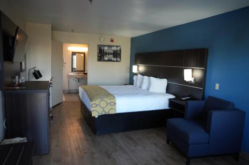 Baymont Inn & Suites في مانينغ: غرفه فندقيه بسرير وكرسي