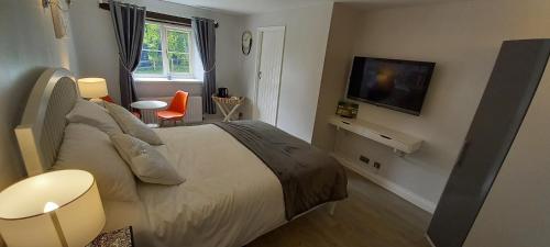 a bedroom with a large bed and a television at Cotswold Merrymouth Inn in Bourton on the Water