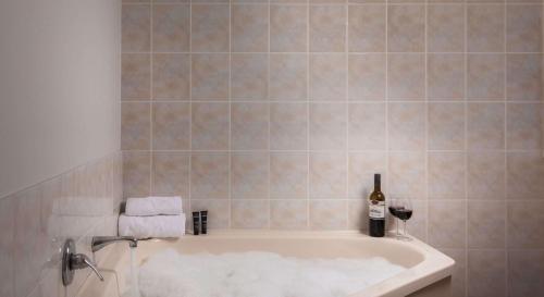 a bathroom with a bath tub with a bottle of wine at Arawa Park Hotel, Independent Collection by EVT in Rotorua