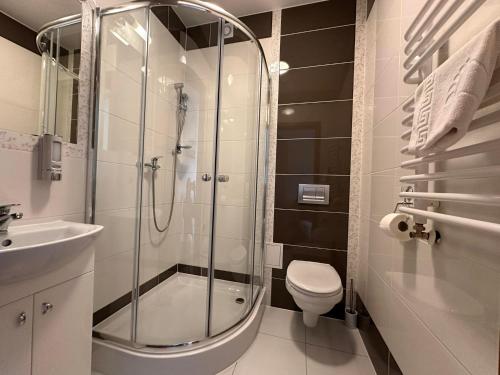 La salle de bains est pourvue d'une douche, de toilettes et d'un lavabo. dans l'établissement Górska Przystań SPA, à Krynica-Zdrój