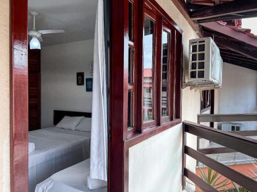 a room with a bed and a balcony with a window at A 200m da praia de Taperapuã Axé Moi 2 suítes, churrasqueira privativa, piscina, sauna portaria 24hrs e internet privativa 300MBPS in Porto Seguro